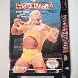May include: A WWF Wrestlemania video game cartridge box featuring Hulk Hogan in a yellow wrestling outfit. The box is blue and black with the text "WWF Wrestlemania" in white. The text "Featuring Hulk Hogan and other WWF Superstars" is also on the box. The box has a Nintendo seal of quality.