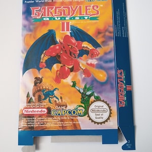 Może przedstawiać: Niebieskie i białe pudełko gry Nintendo dla Gargoyles Quest II, gry wideo zaprojektowanej przez Capcom. Pudełko przedstawia czerwoną gargulę z skrzydłami, która lata w powietrzu i pluje ogniem. Tekst na pudełku brzmi "Gargoyles Quest II" i "Licencja Nintendo do gry na systemie rozrywki Nintendo".