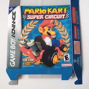May include: A blue, red and yellow Game Boy Advance game cartridge box for Mario Kart: Super Circuit. The box features a cartoon image of Mario driving a red kart with a yellow star on the side. The text "Mario Kart: Super Circuit" is printed in white on a blue background. The ESRB rating "Everyone" is displayed on the box.