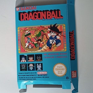 Może przedstawiać: Niebieskie i białe pudełko na kartridż gry Nintendo do gry Dragonball. Pudełko zawiera rysunkową grafikę Goku, głównego bohatera anime Dragonball, walczącego z smokiem. Pudełko zawiera również tekst "The Adventure Begins!" i "L'Aventure Commence!"