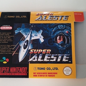 Puede incluir: Caja del juego Super Aleste para Super Nintendo. La carátula presenta una nave espacial y una figura con traje espacial. La caja es amarilla y negra con el logotipo de Super Nintendo y el texto "Super Aleste".