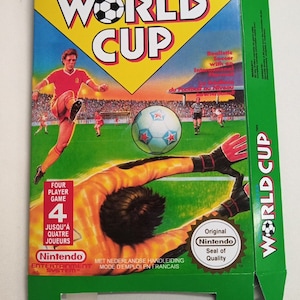 以下が含まれることがあります： 緑、黄色、白の任天堂ワールドカップゲームボックス。サッカー選手がボールを蹴り、ゴールキーパーがボールをブロックするためにダイビングしている様子が描かれています。ボックスには「4人プレイゲーム」と「任天堂オリジナル品質保証」の文字が書かれています。