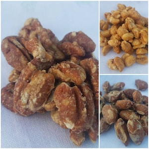 May include: A close-up of a pile of pecan halves and whole pecans coated in a sweet glaze. The pecans are a light brown color and have a slightly crunchy texture.