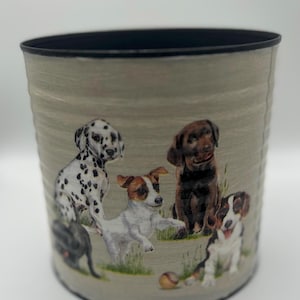 May include: A cylindrical container with a black rim and a light green exterior. The container is decorated with images of several different dog breeds, including a Dalmatian, a Jack Russell Terrier, and a Labrador.
