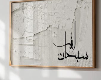 May include: A framed abstract art piece with a textured, off-white surface. The artwork features black Arabic calligraphy and is encased in a thin, gold-colored frame. The piece is mounted on a white wall.