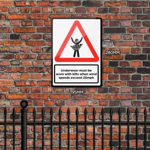 May include: A rectangular sign, 7.6 inches wide and 11 inches tall, with a black border, mounted on a brick wall. The sign features a red triangle with a person in a kilt and the text "Underwear must be worn with kilts when wind speeds exceed 25mph."