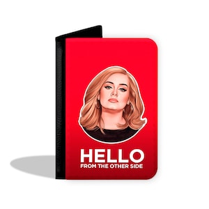 May include: Red passport holder with a black border. The front features a cartoon illustration of Adele with the text "HELLO FROM THE OTHER SIDE".
