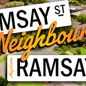 Puede incluir: Un primer plano de una señal de calle que dice "Ramsay St." con la palabra "Neighbours" en una fuente estilizada superpuesta sobre la señal. La señal está ubicada sobre un fondo de casas suburbanas con césped verde.