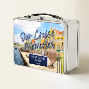 Puede incluir: Una fiambrera de metal plateado con una imagen panorámica de un pueblo costero. La imagen presenta edificios coloridos, un cielo azul y el texto "Our Cruise Memories". Un rectángulo azul oscuro en la parte inferior dice "YOUR CRUISE NAME DATE."