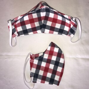 May include: Two red, white, and black plaid face masks with elastic ear loops. The masks are made of fabric and have a checkered pattern.