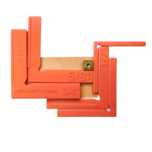 May include: Orange plastic leather crafting tools with measurements in inches, including 1/2 in, 3/8 in, 5/8 in, 3/4 in, and 1 in. The tools are arranged in a shape resembling a letter L. The text "Hella Leather Company" is printed on the tool.