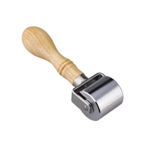 May include: A silver metal roller with a wooden handle. The roller is used for smoothing leather or other materials.