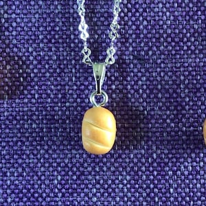 Puede incluir: Tres collares de plata con un pequeño dije de pan marrón y dos pendientes de plata con un pequeño dije de pan marrón.