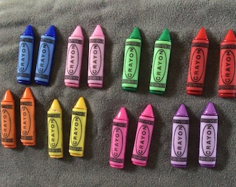 May include: A collection of 14 crayons in various colors, including red, orange, yellow, green, blue, pink, and purple. Each crayon has the word "CRAYON" printed on it.