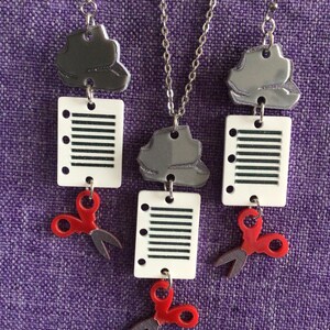May include: A set of silver and red earrings and a necklace featuring a paperclip, a sheet of paper with lines, and a pair of scissors.