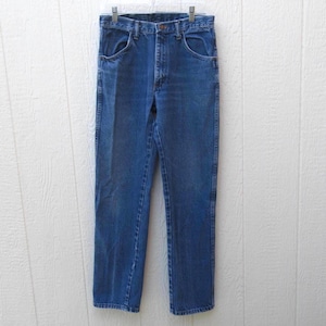 May include: Blue denim jeans hanging on a clear plastic hanger. The jeans have a classic five-pocket design, a button and zipper closure, and a straight leg cut. The denim has a medium wash with some fading.