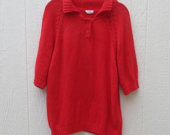 May include: A bright red sweater with a collared neckline and three buttons. The sweater has three-quarter sleeves and decorative stitching on the shoulders. The garment is hanging on a black hanger.