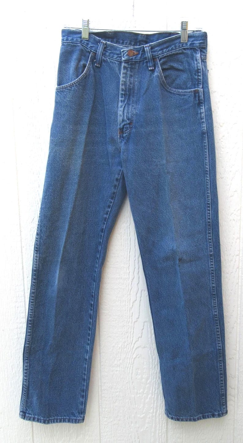 May include: Blue denim jeans with a classic five-pocket design. The jeans are hung on a metal hanger and feature a button and zipper closure. The pants have a straight leg cut and are made of a durable denim material.