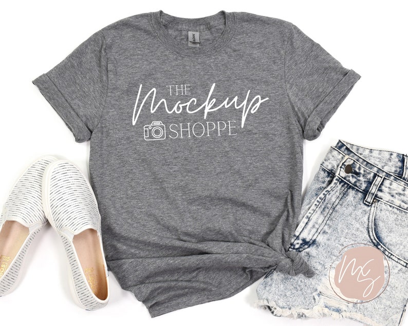 May include: Gray heather t-shirt with a white graphic of a camera and the text "The Mockup Shoppe".