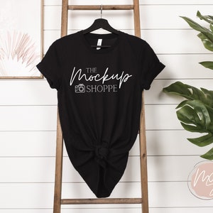 Puede incluir: Camiseta negra con un gr&aacute;fico blanco que dice "The Mockup Shoppe" y un icono de c&aacute;mara.