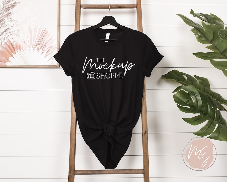 Puede incluir: Camiseta negra con un gr&aacute;fico blanco que dice "The Mockup Shoppe" y un icono de c&aacute;mara.