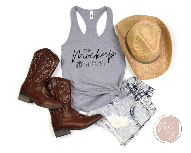 May include: A gray tank top with the text "THE MockUp SHOPPE" and a camera icon. The tank top is styled with denim shorts, cowboy boots, and a straw cowboy hat.