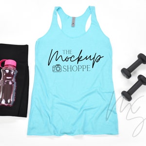 May include: A light blue tank top with the text "THE MockUp SHOPPE" in black lettering. The tank top is lying flat on a white surface with black leggings, a pink water bottle, and two black dumbbells.