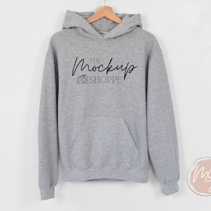 May include: Gray hooded sweatshirt with a black pocket and the text "THE MockUp SHOPPE" printed on the front.