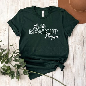 Może przedstawiać: Zielony T-shirt z białym nadrukiem z napisem "The MockUp Shoppe" i aparatem fotograficznym z sercem w środku.