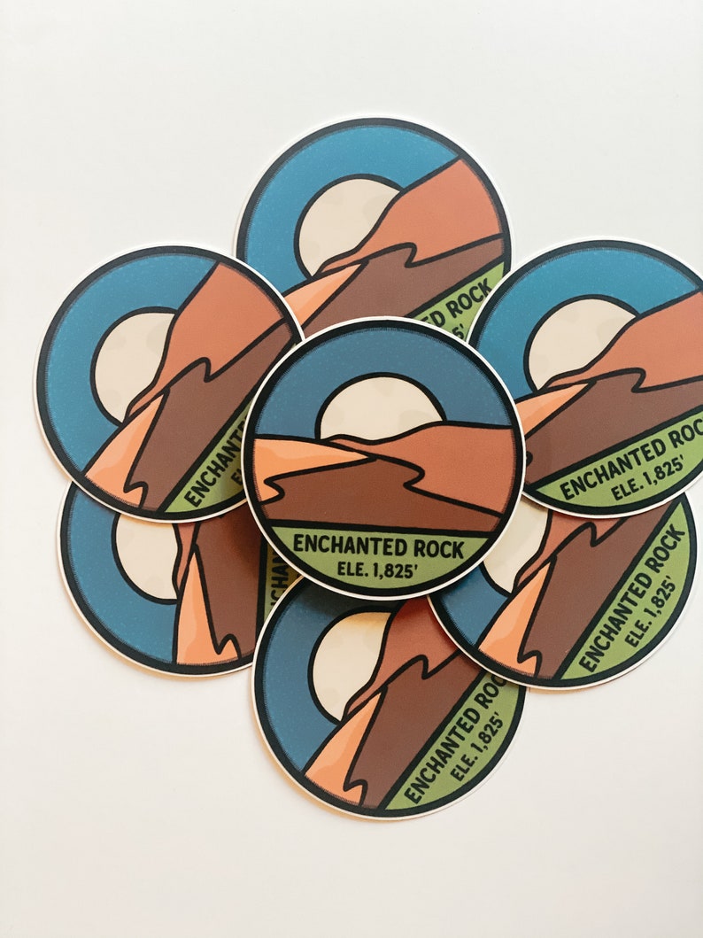 Puede incluir: Un conjunto de pegatinas redondas con un dise&ntilde;o de paisaje que presenta una monta&ntilde;a, un sol y el texto "ENCHANTED ROCK ELE. 1,825'". Las pegatinas tienen una combinaci&oacute;n de colores azul, marr&oacute;n, naranja y crema.