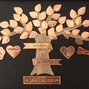 May include: A copper family tree with leaves, hearts, and a bone hanging from the branches. The names Michael, Sophia, Thomas, Luna, Alice, and Finn are engraved on the ornaments. The date April 27, 2016 is engraved on a banner at the bottom.