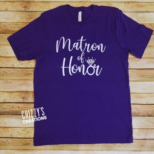 May include: Purple t-shirt with the text "Matron of Honor" in white with a diamond ring graphic.