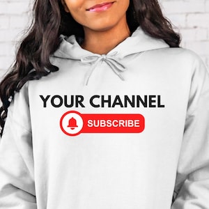 以下が含まれることがあります： 「YOUR CHANNEL」という文字と、赤いボタンにベルのアイコンと「SUBSCRIBE」という文字が書かれた白いパーカー