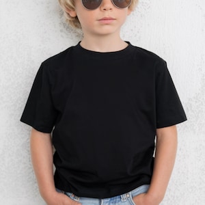 May include: A black crew neck t-shirt. The short-sleeved shirt is worn by a person wearing sunglasses and blue jeans. The shirt is made of a soft, comfortable material.