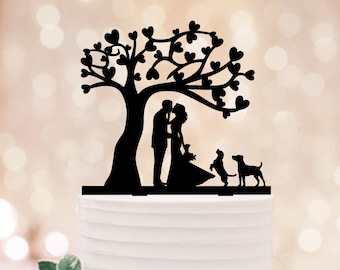 May include: Black silhouette cake topper featuring a couple kissing under a tree with hearts, and two dogs standing beside them.