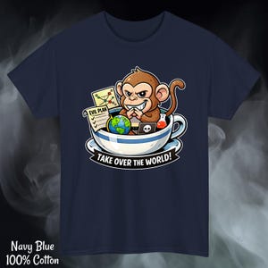 May include: Navy blue, 100% cotton t-shirt featuring a cartoon monkey in a teacup with the text "TAKE OVER THE WORLD!". The monkey has an evil grin and is surrounded by a laptop, a globe, and an "EVIL PLAN" document.