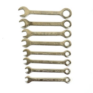 May include: A set of eight silver wrenches of varying sizes, arranged on a white background. Each wrench is marked with its size in inches, with both open-end and box-end designs. The brand name "DEWALT USA" is visible on each wrench.