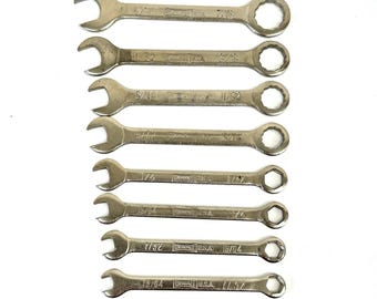 May include: A set of eight silver wrenches of varying sizes, arranged on a white background. Each wrench is marked with its size in inches, with both open-end and box-end designs. The brand name "DEWALT USA" is visible on each wrench.