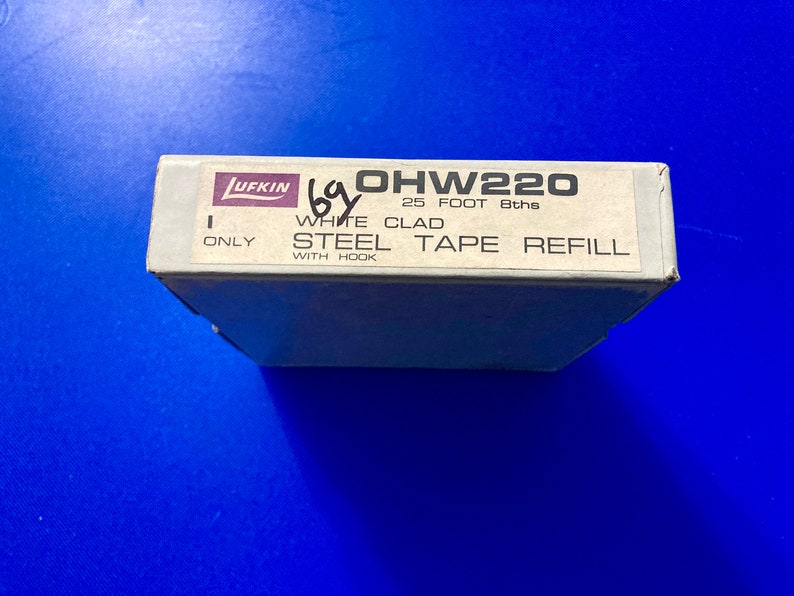 May include: A white box with black text that reads "OHW220 25 FOOT 8ths ONLY WHITE CLAD STEEL TAPE REFILL WITH HOOK" and a purple logo that reads "LUFKIN".