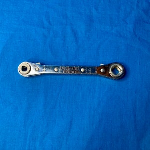May include: A silver adjustable wrench with a square head on one end and a round head on the other. The wrench is labeled "DEVCO DE 680".