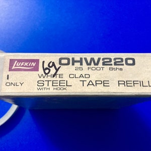 May include: A white box with the text "Lufkin OHW220 25 FOOT 8ths WHITE CLAD STEEL TAPE REFILL ONLY WITH HOOK" printed on it.