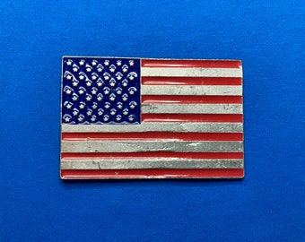 Könnte beinhalten: Eine kleine, silberfarbene amerikanische Flaggennadel mit roter, weißer und blauer Emaille. Die Flagge hat 13 Streifen und 50 Sterne.