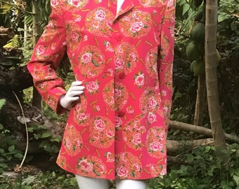 Può includere: Un blazer rosa con motivo floreale, chiusura con bottoni e colletto alla coreana. Il blazer ha le spalle imbottite e una lunghezza leggermente corta.