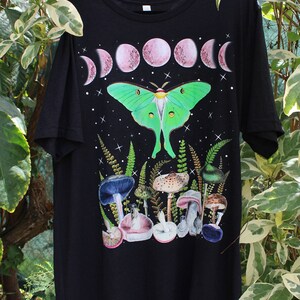 May include: Black t-shirt with a green luna moth, pink moon phases, and mushrooms printed on the front.