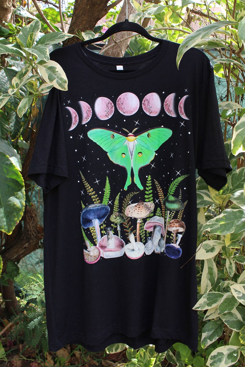 May include: Black t-shirt with a green luna moth, pink moon phases, and mushrooms printed on the front.