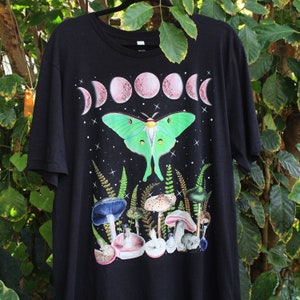 May include: Black t-shirt with a green luna moth, pink moon phases, and mushrooms printed on the front.