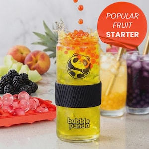 Könnte beinhalten: Ein erfrischendes gelbes Getränk in einem Glas mit schwarzem Griff, mit einem Panda-Logo und dem Text "Bubble Panda". Das Getränk ist mit orangefarbenen Kugeln garniert und von Früchten wie Pfirsichen, Brombeeren und Eiswürfeln umgeben. Ein roter Kreis zeigt "Popular Fruit Starter".