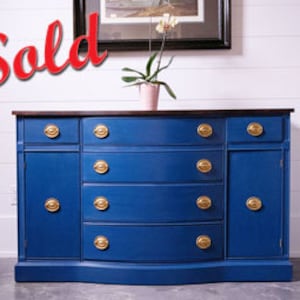 May include: A vintage blue painted sideboard with a dark wood top and gold hardware. The sideboard has four drawers and two doors.