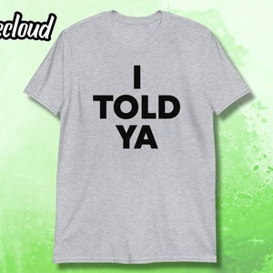 Könnte beinhalten: Ein graues T-Shirt mit dem Text "I TOLD YA" in Schwarz gedruckt.