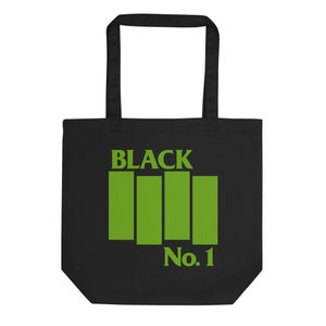 以下が含まれることがあります： 黒いトートバッグ。緑色の文字とグラフィックが特徴です。バッグには、4つの緑色の縦棒の上に「BLACK」という文字があり、その下に「No. 1」と書かれています。バッグには、持ち運び用の黒いハンドルが2つ付いています。